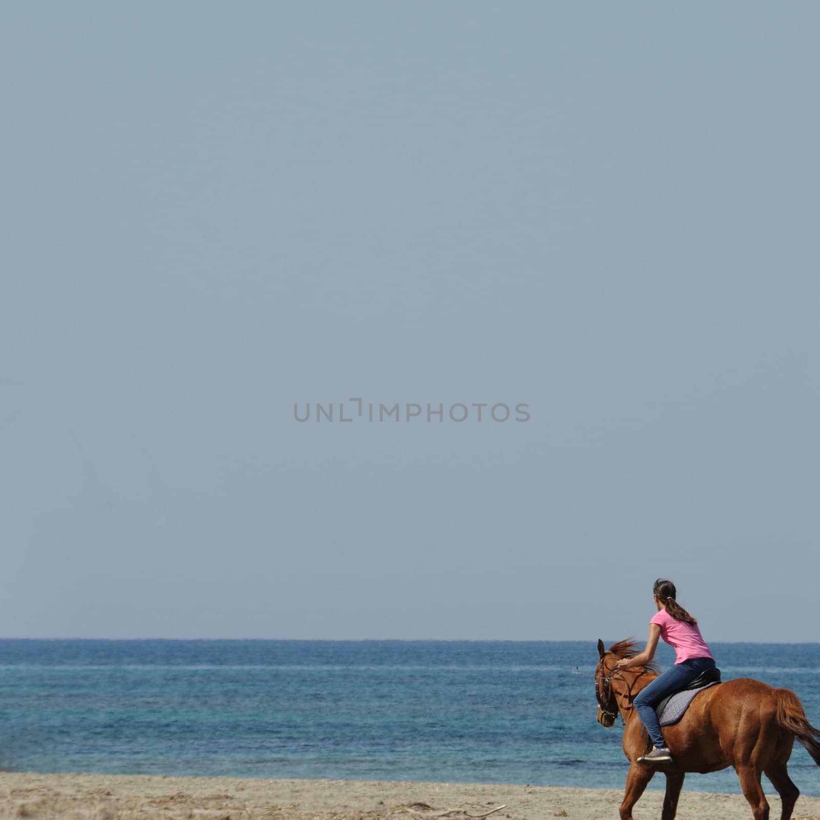 KYLLINI, GREECE - MAY 2: Young woman horse riding on empty beach, Kyllini Greece, May 2, 2012.