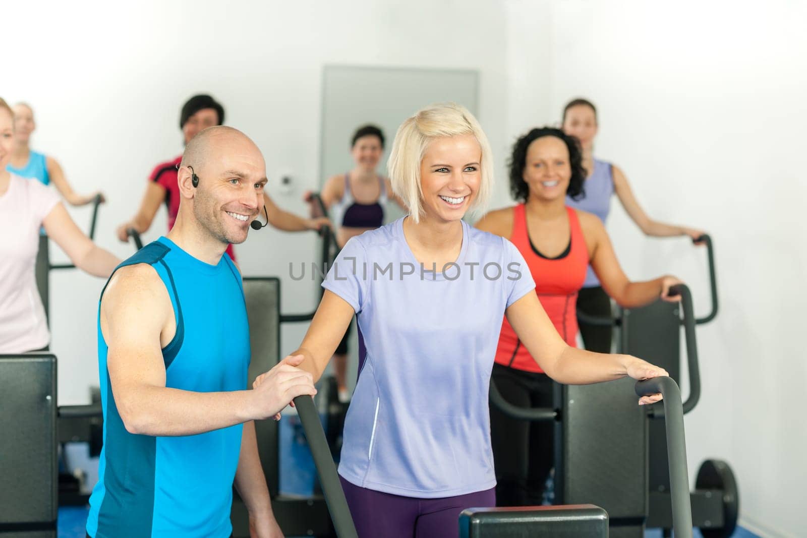Fitness instructor with gym people exercise on cross-trainer