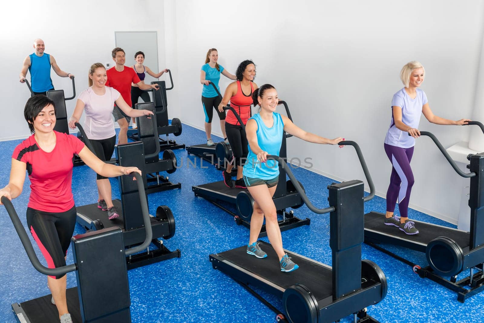 Fitness class walking on treadmill running deck at health club