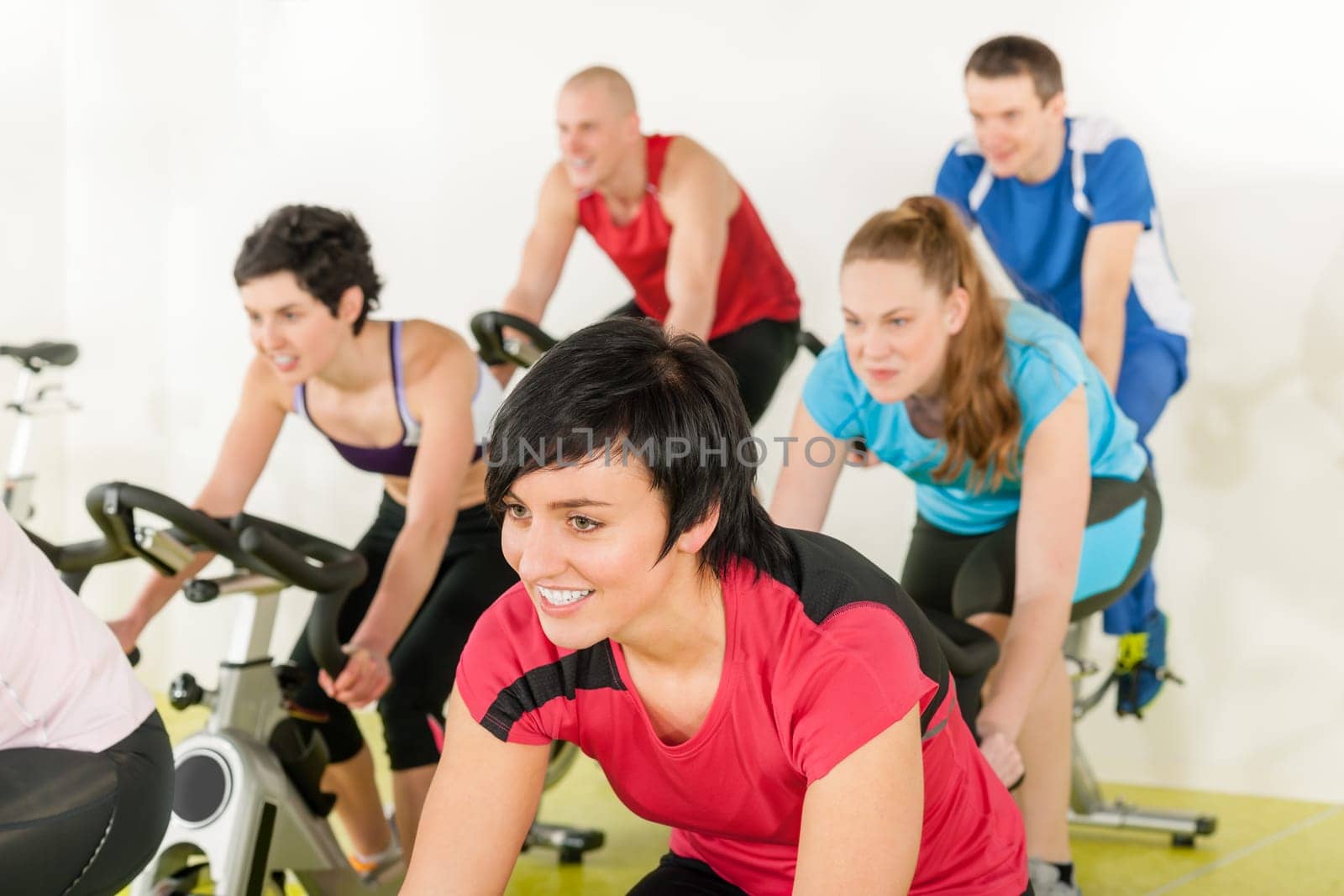 Fitness group of people on bicycle doing spinning at gym
