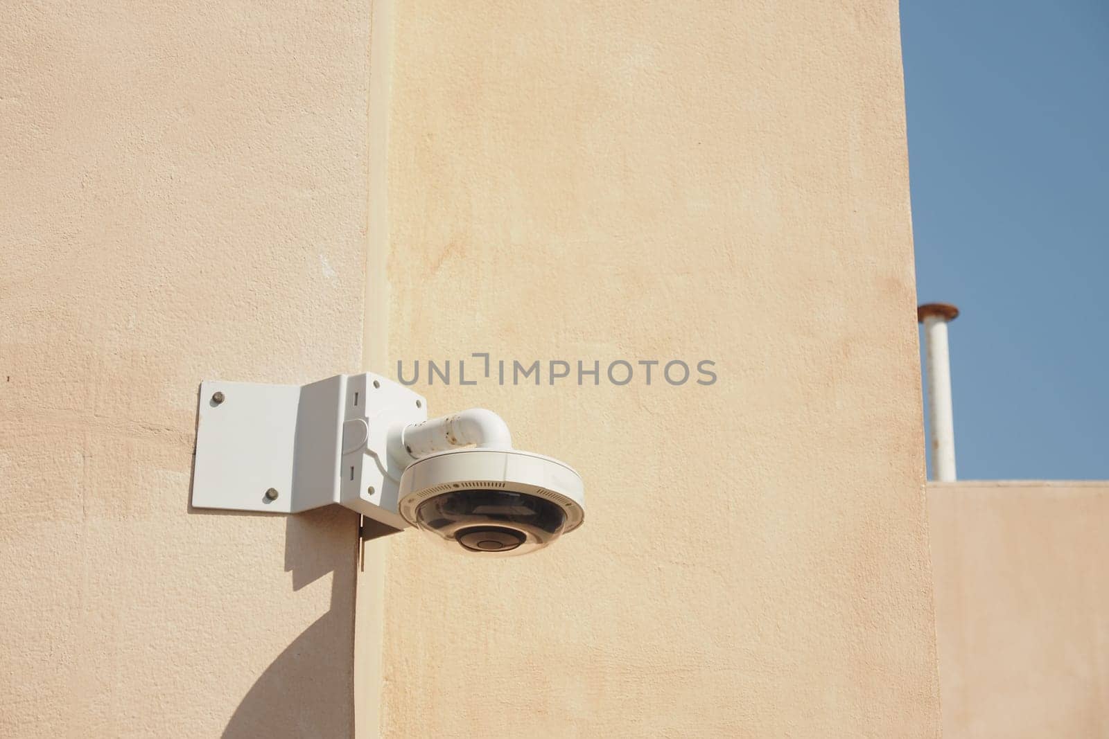 A high-resolution security camera is attached to a light-colored wall.