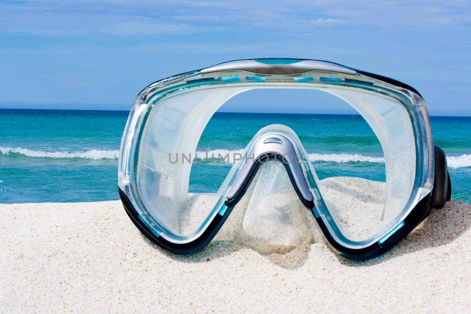 Diving equipment mask on white sand beach.
