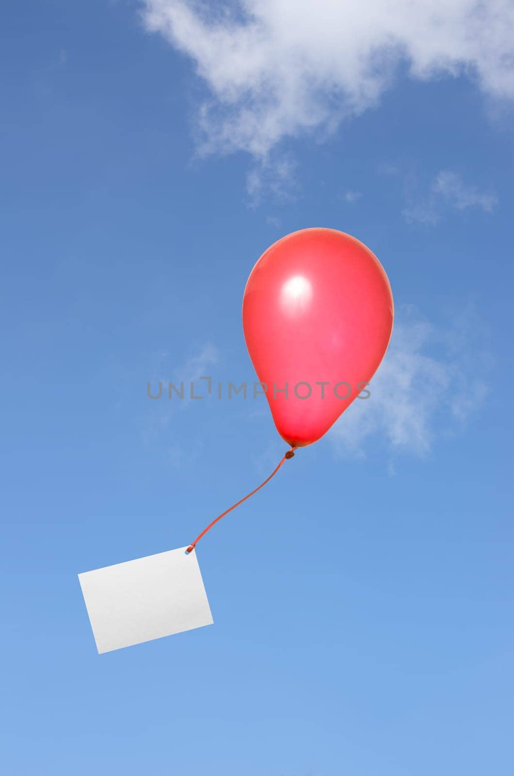 Red balloon with greeting card against blue sky