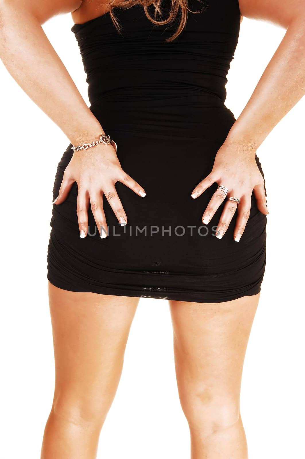 A young woman in a black dress standing and holding her nice butt, in a closeup shoot of her torso foe white background.