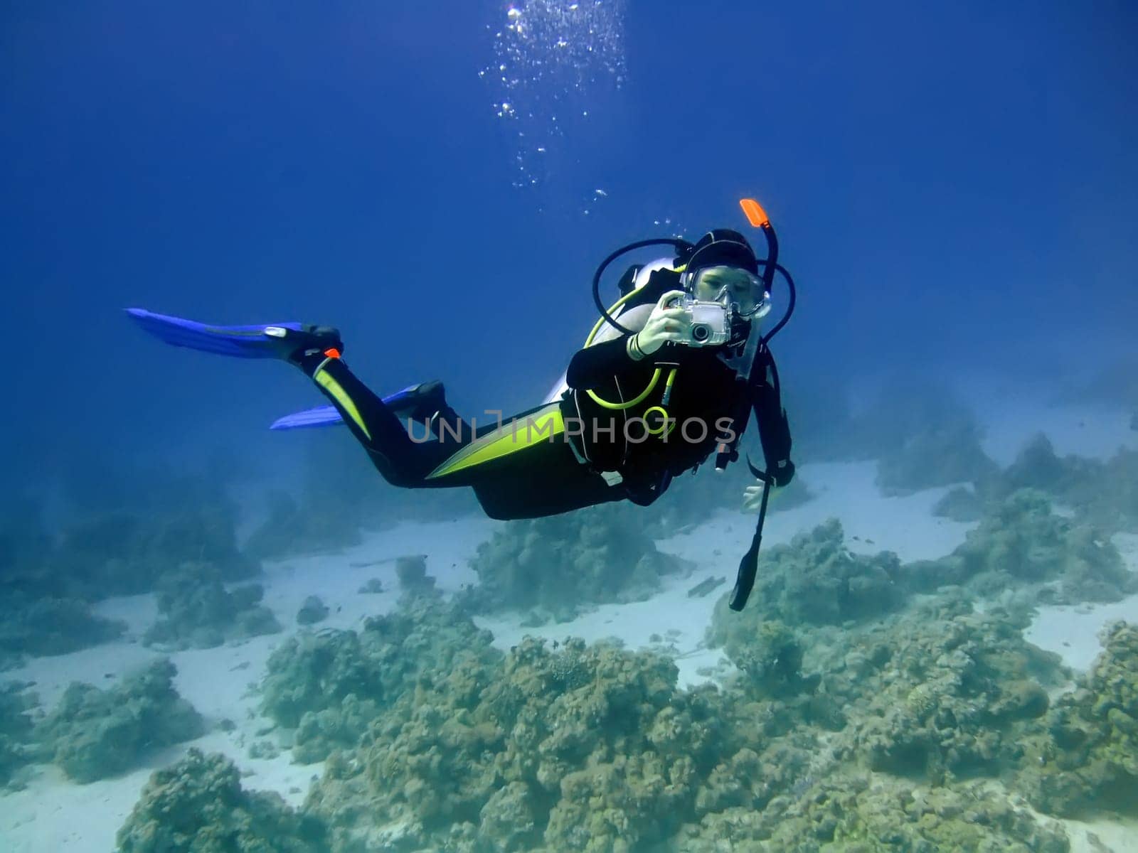 Diver with camera in deep and bubbles. Underwater photographer