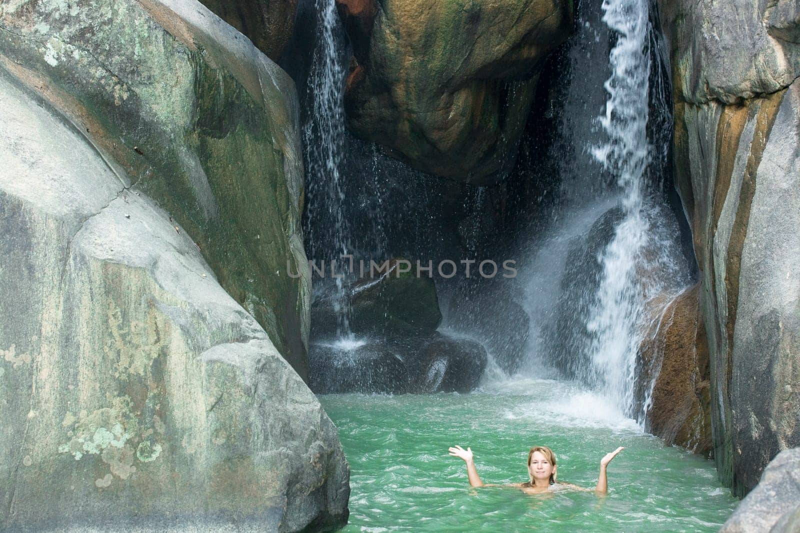 Young woman swimming in waterfall pool