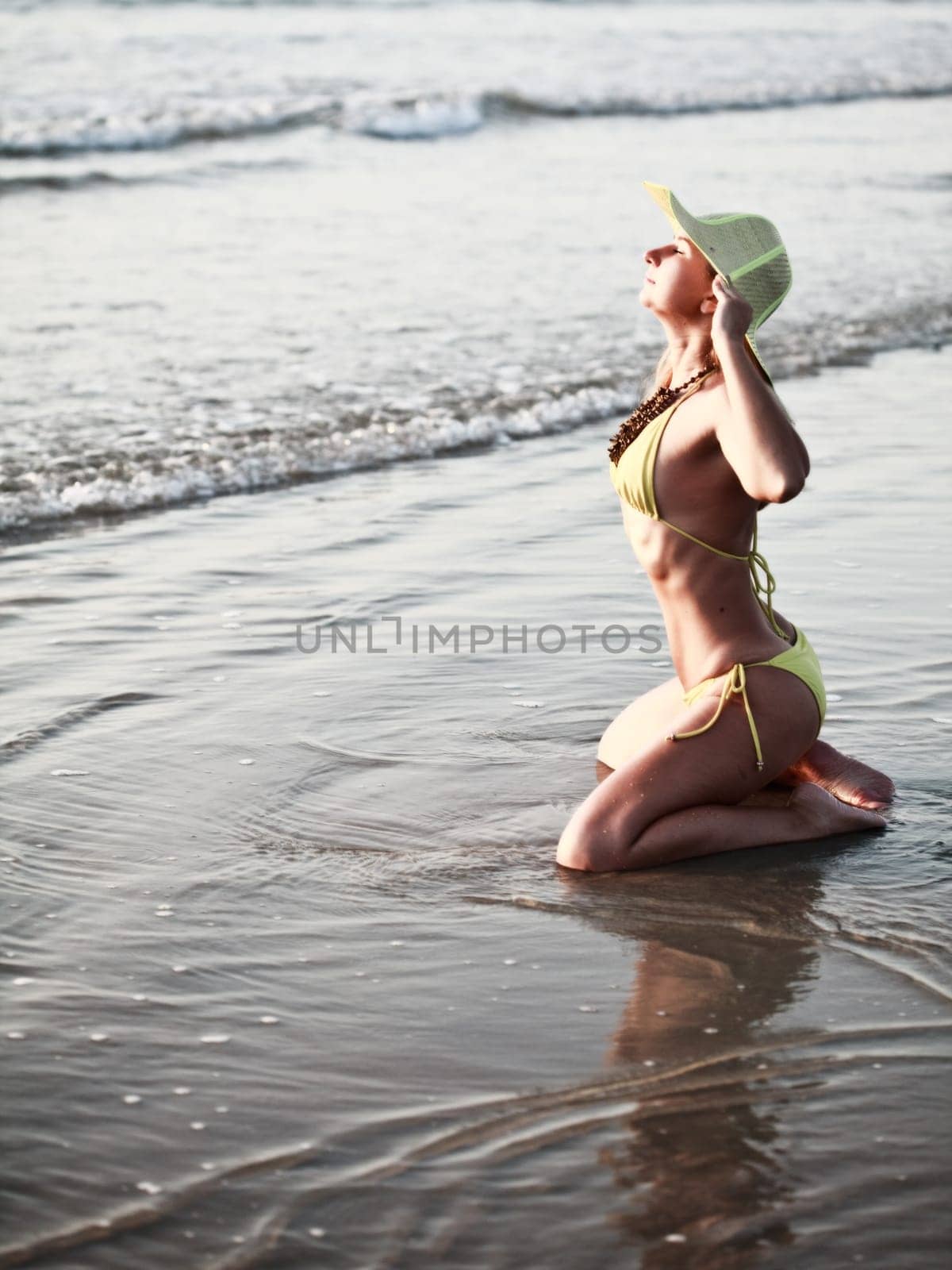 Young woman sunbathing on the beach in bikini