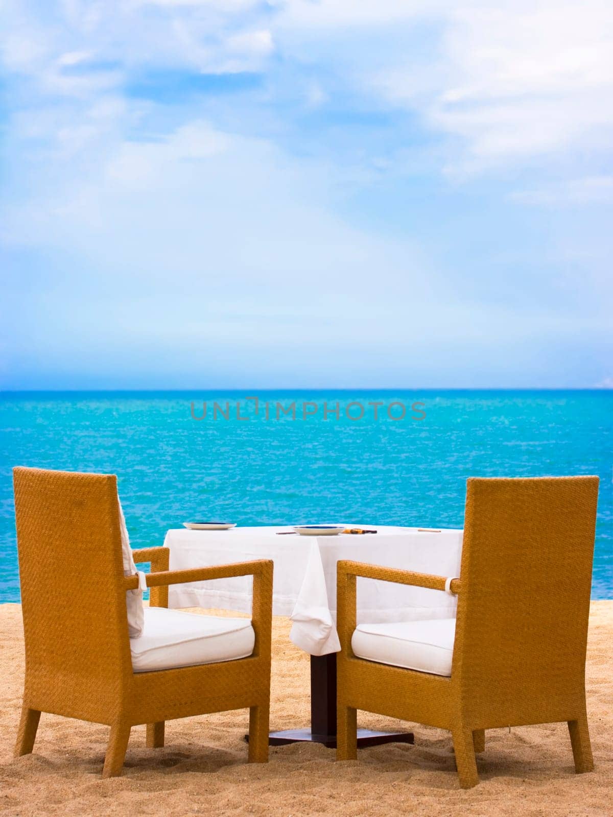 Dining table on white sand beach close to the ocean