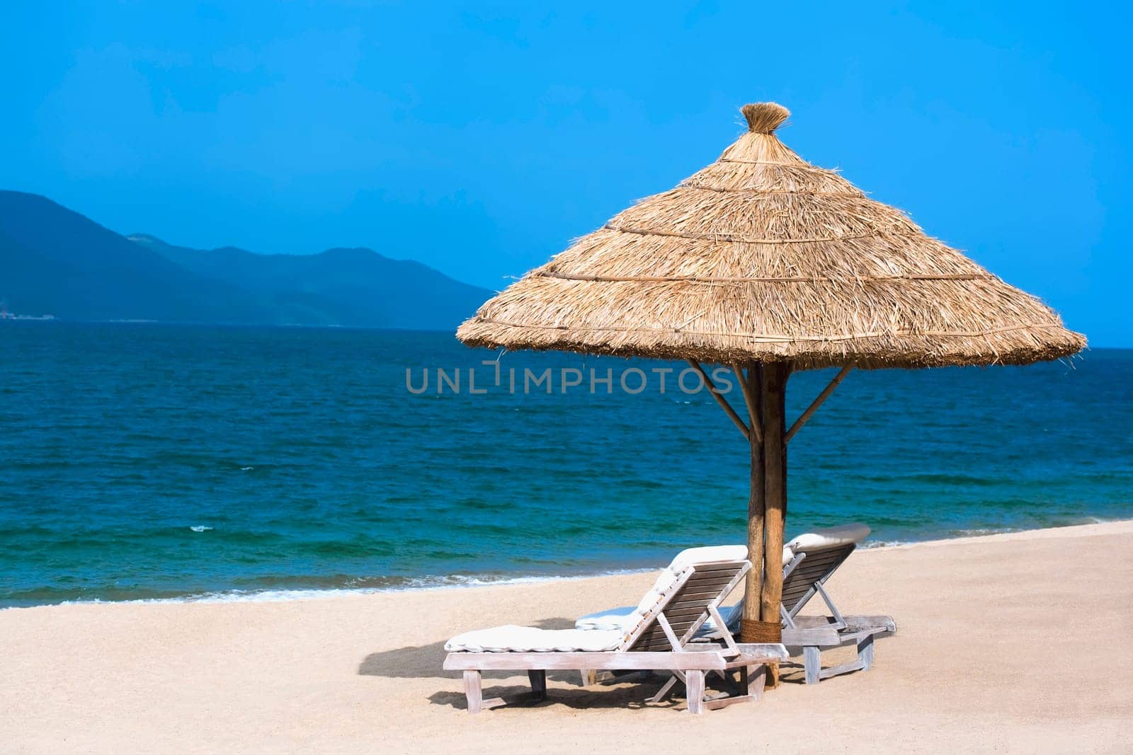 Two beach chairs on white sandy tropical beach