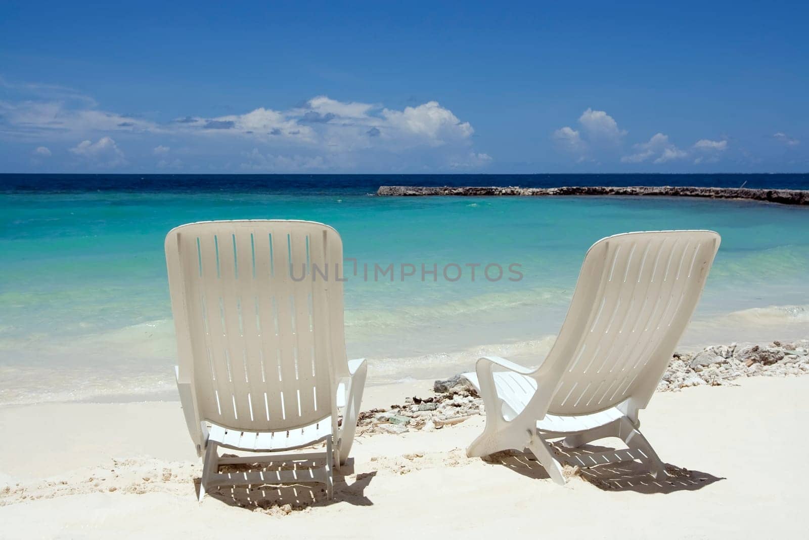 Two beach chairs on a clean, sunny beach. Maldives