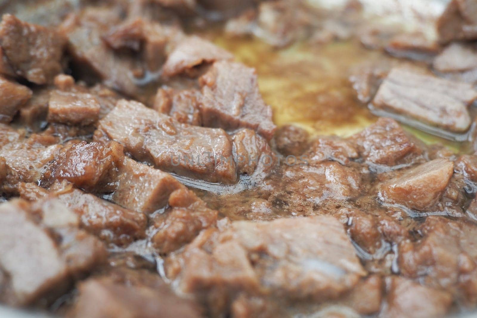 Chunks of beef sizzle in oil, releasing rich aromas in the kitchen.