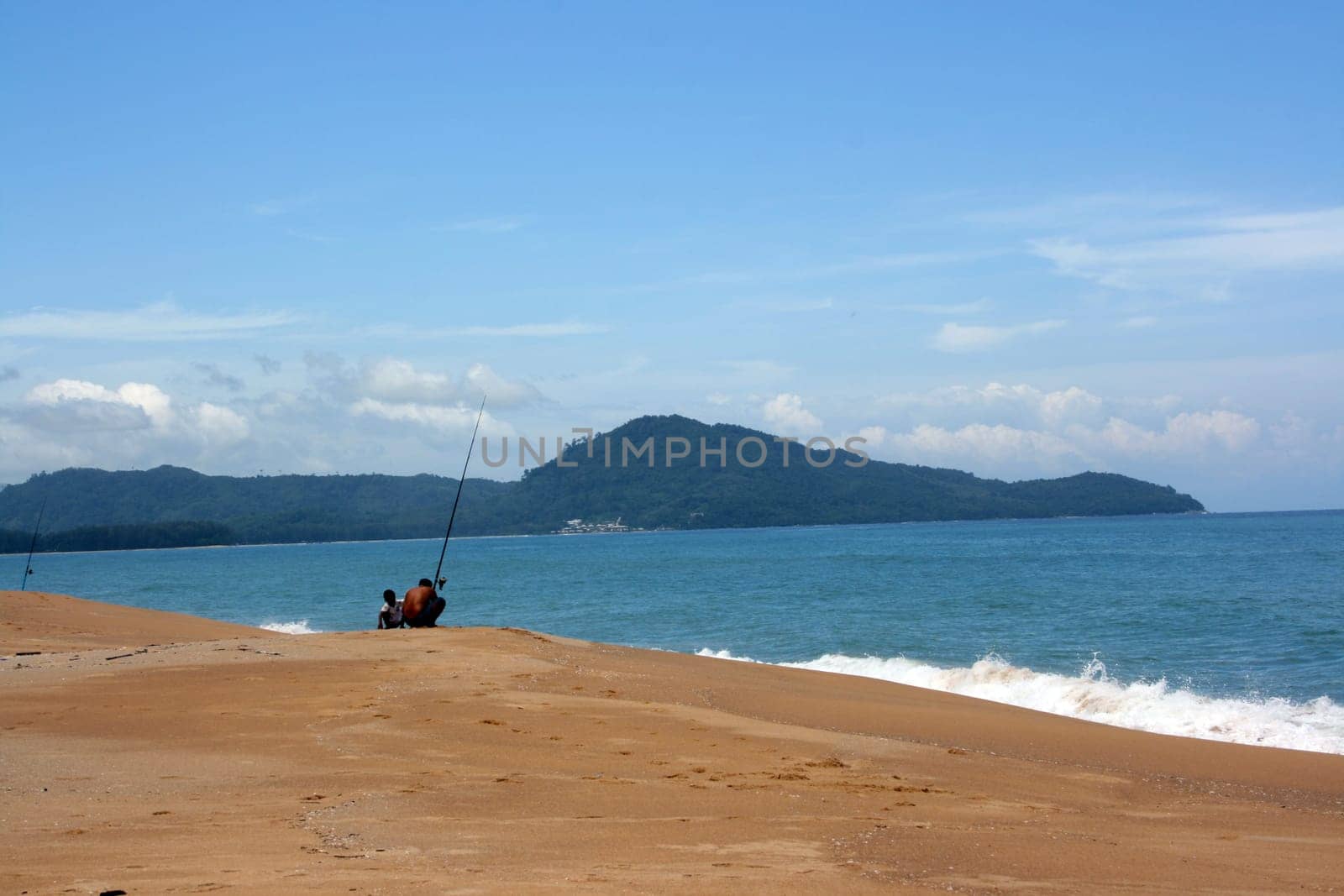 Fisherman with his son on the sandy beach of the ocean
