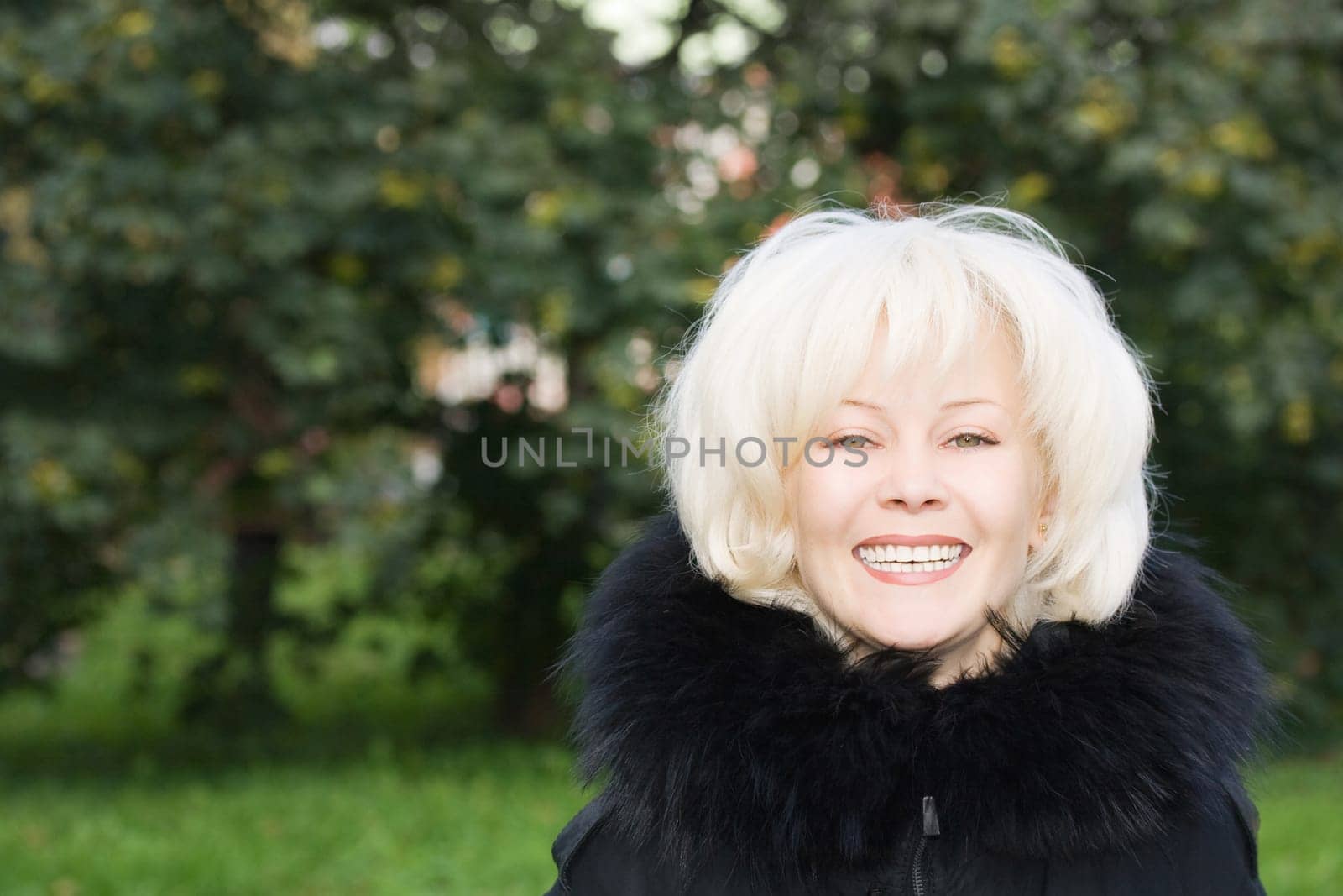 Portrait of young smiling woman on natural green background