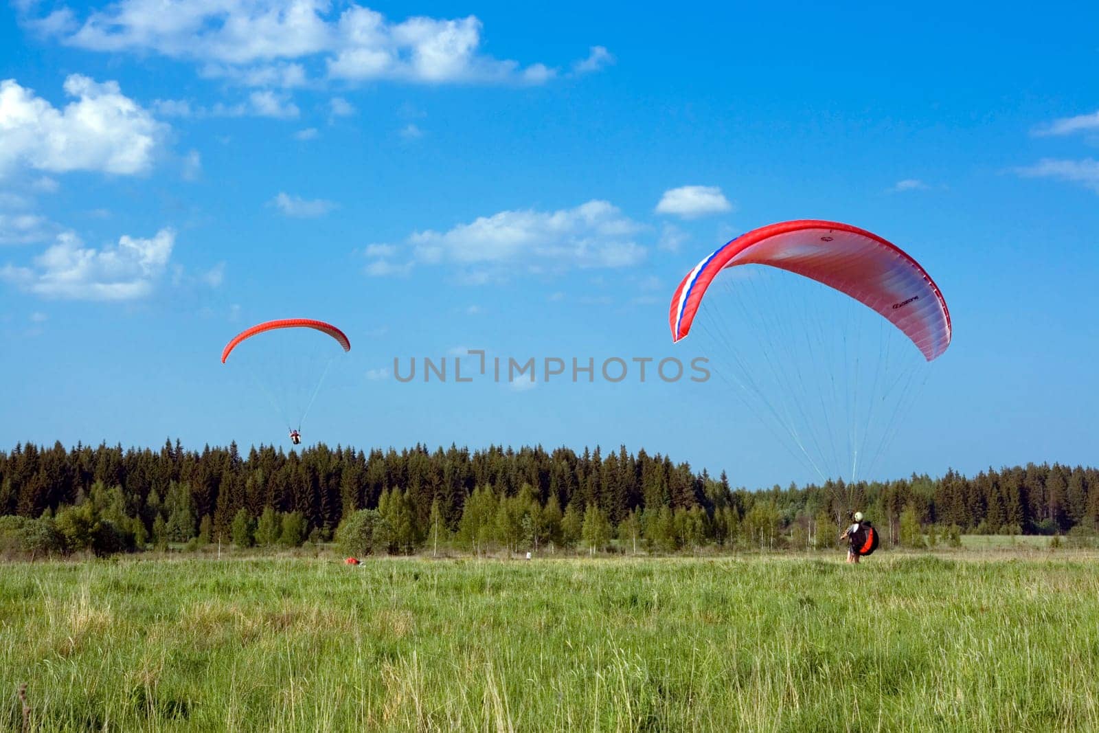 Two paragliders with red wings