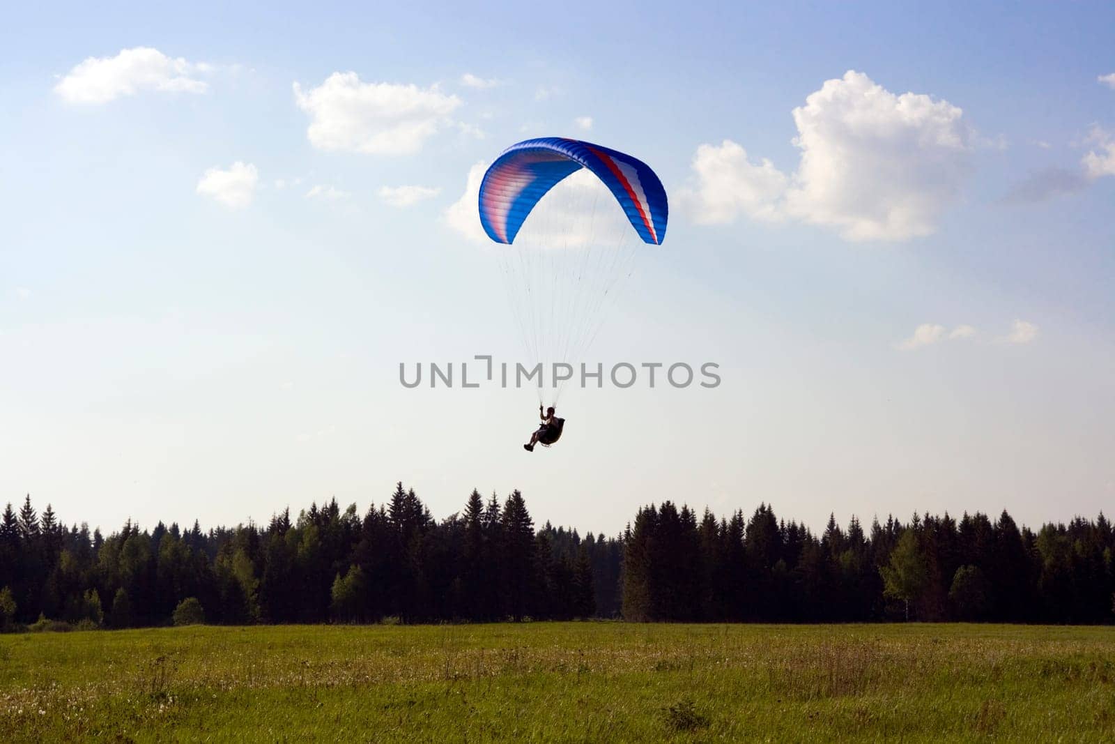 Paraglider landing with blue wing