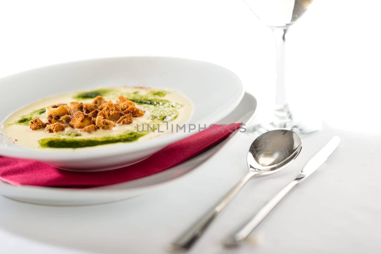Creamy soup with garlic, spinach and croutons in white plate