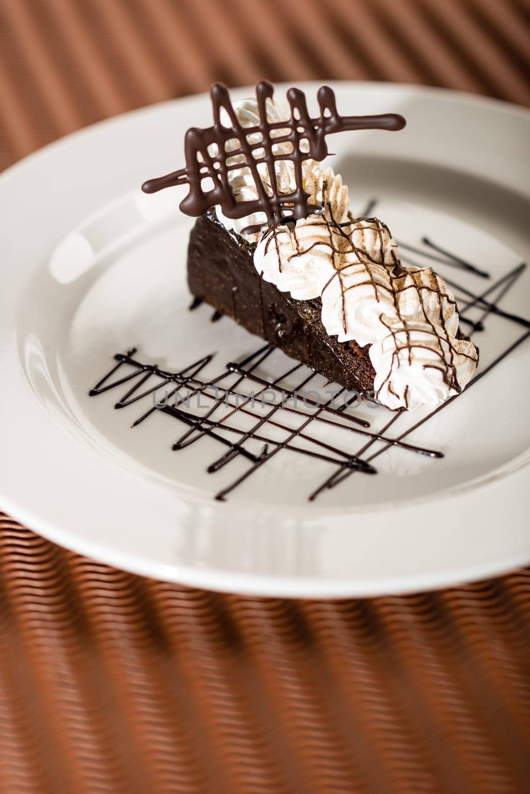 Sacher cake with whipped cream and chocolate on cocoa background