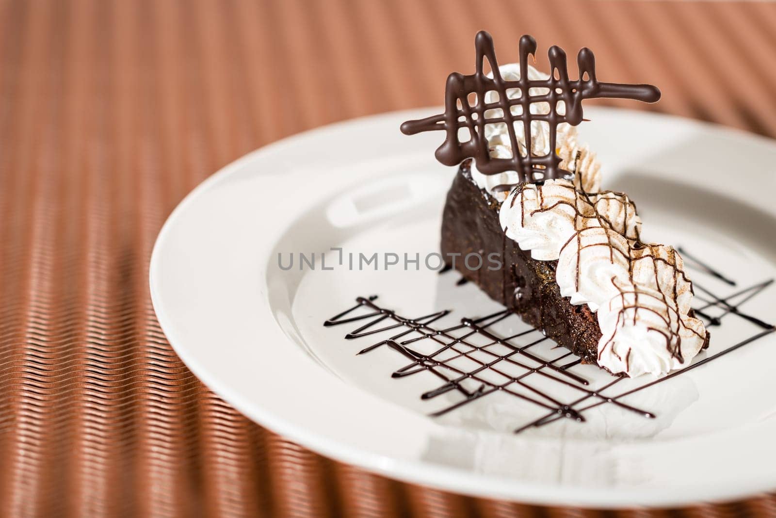 Sacher cake with whipped cream on chocolate background