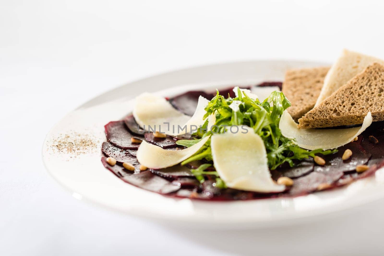Vegetarian carpaccio with beetroot,nuts and toast on white background