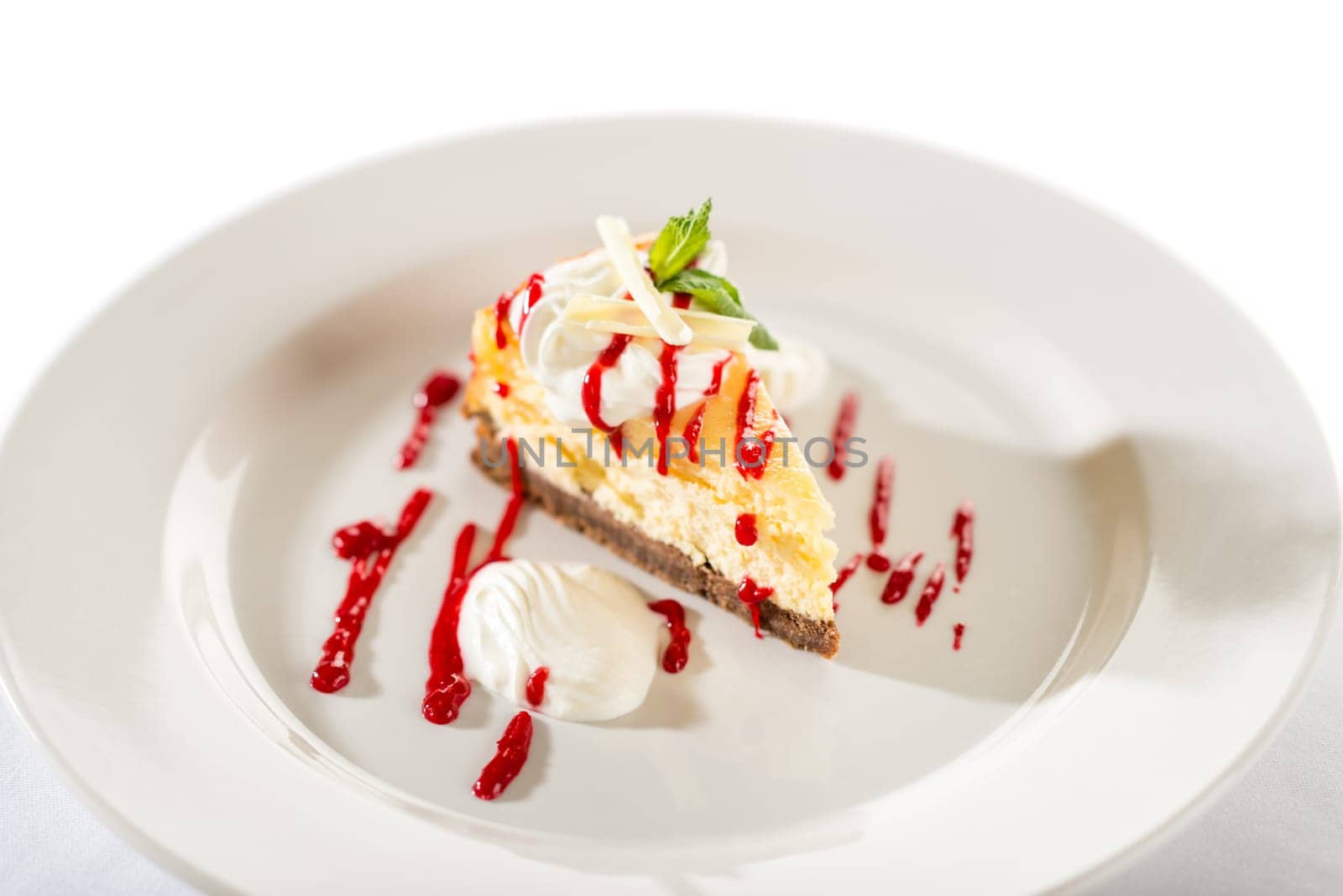 Delicious cheesecake with raspberry sauce on white plate and isolated