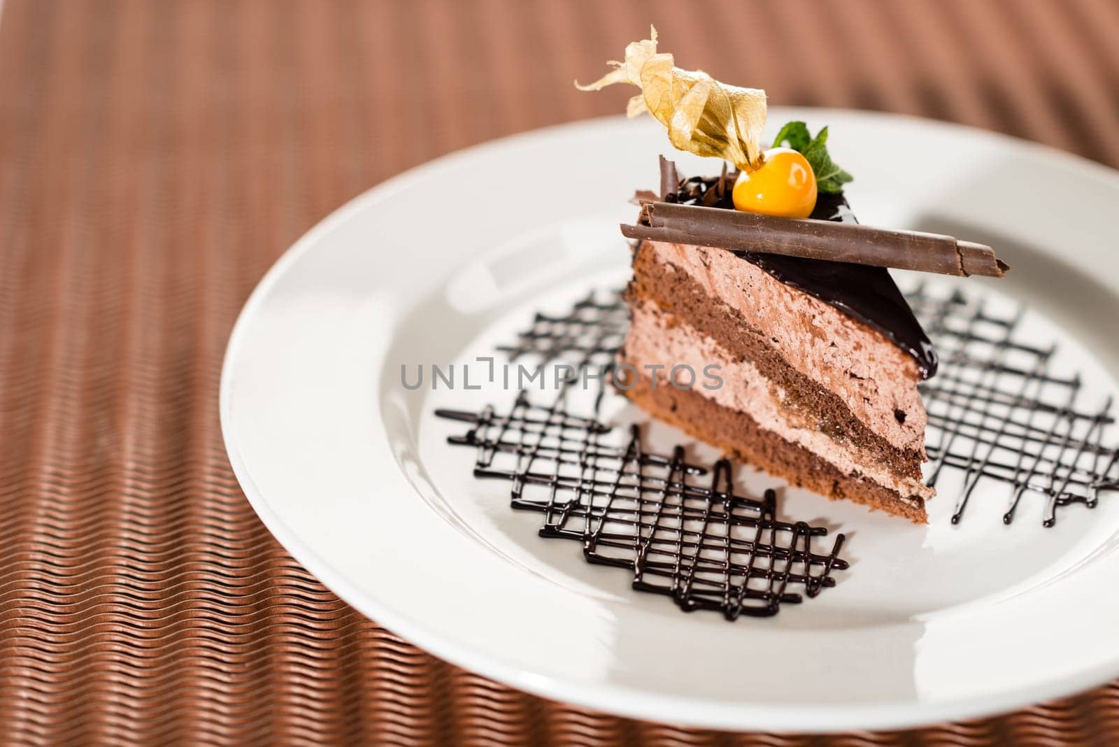 Delicious chocolate cake with physalis on white plate cocoa background