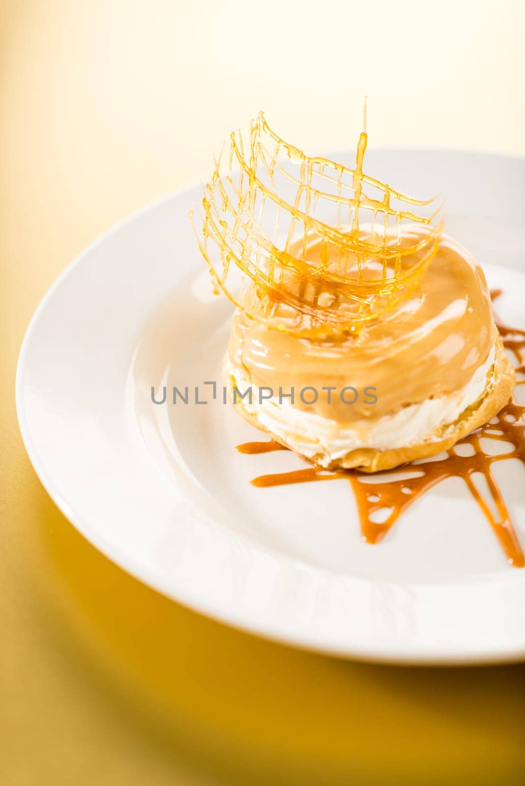 Delicious creamy dessert with caramel topping on yellow background