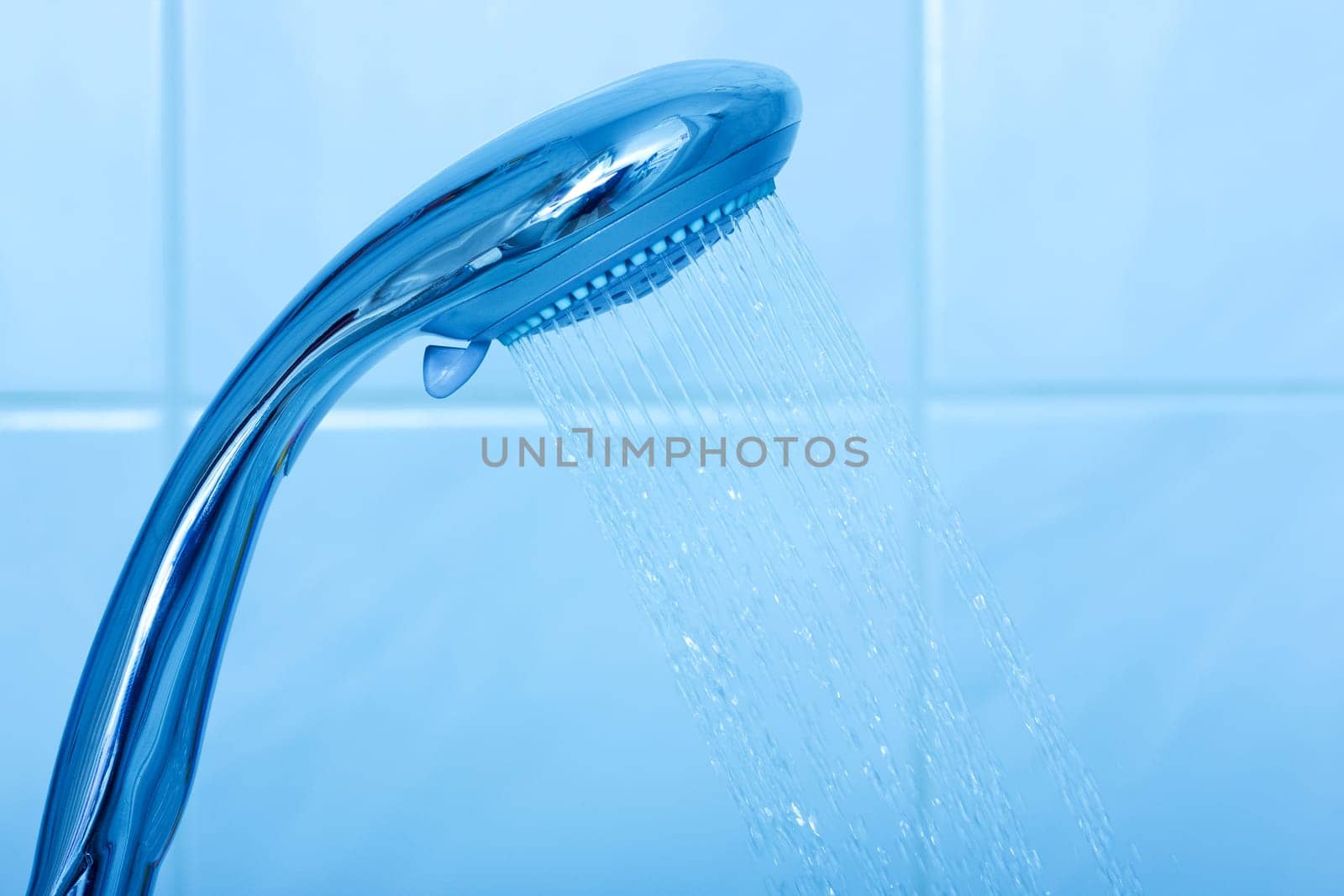 Shower head with water stream on blue background