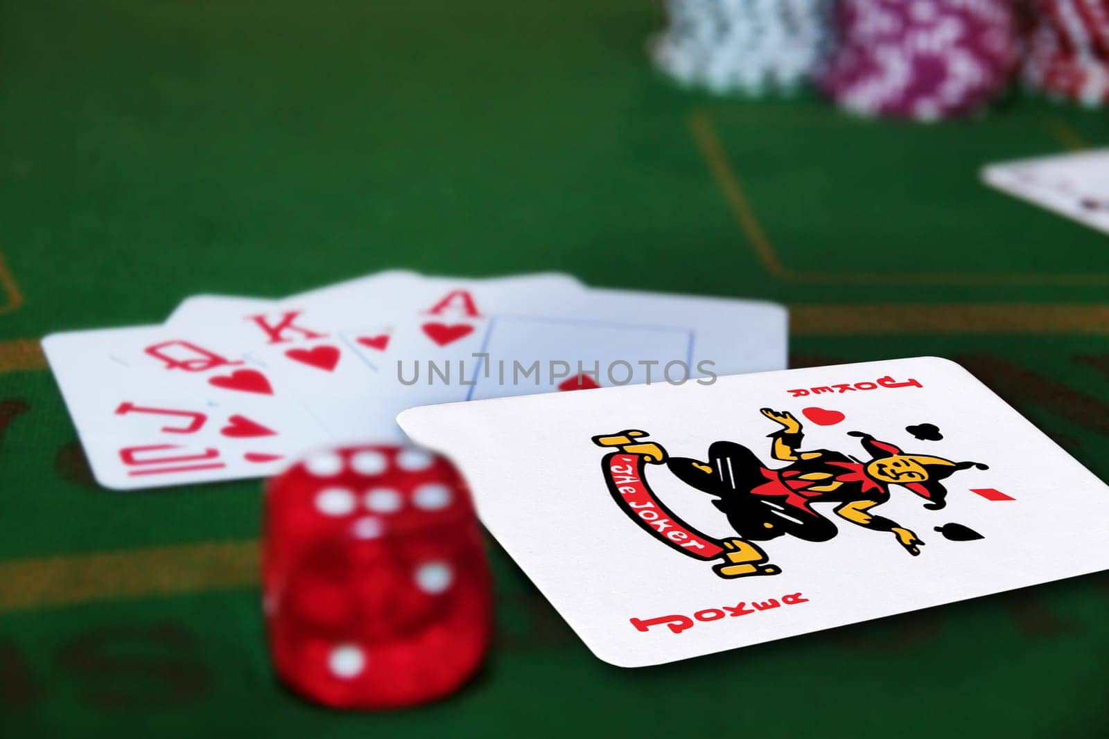green casino table with dice and a hand of a royal flush in a poker game and a joker in the pack