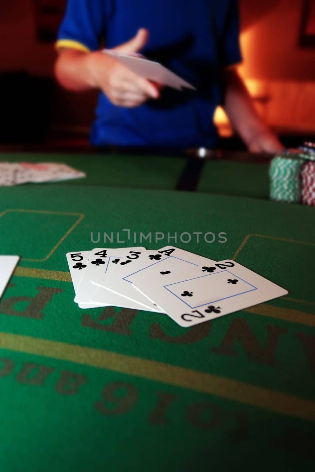 poker player throwing in cards with a straight flush of clubs in the foreground