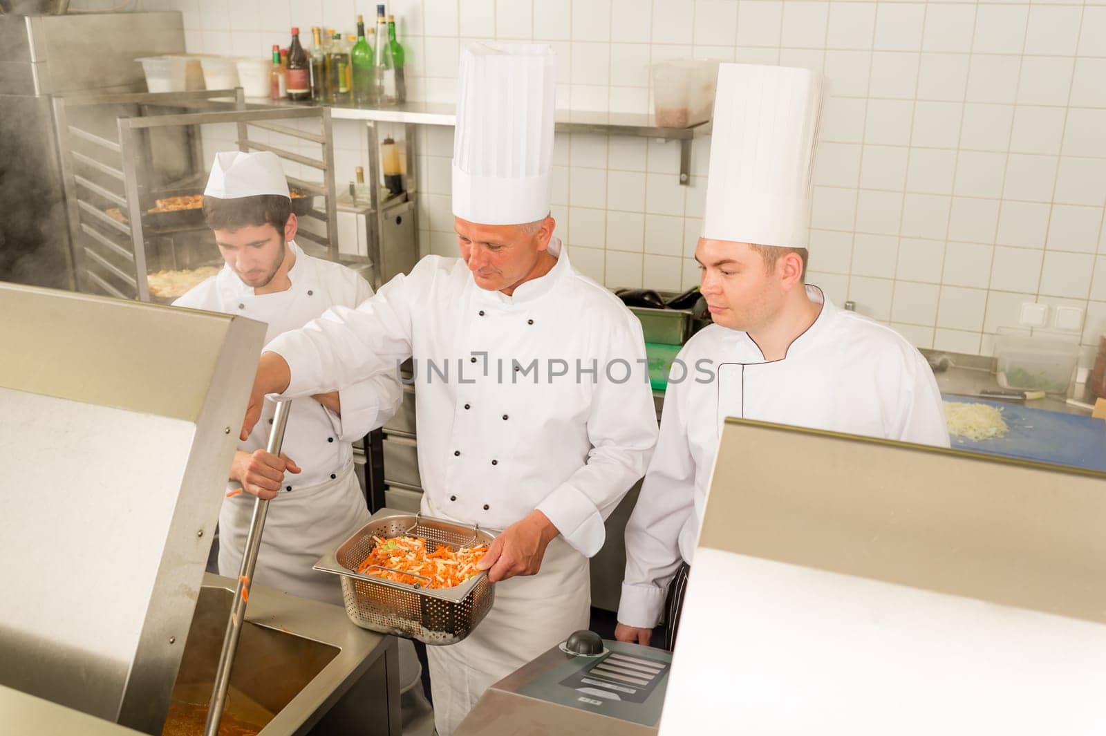 Professional chef cook with team prepare food in industrial kitchen