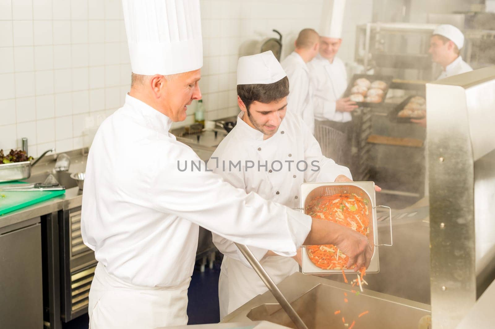 Professional chef cook with team prepare food in industrial kitchen