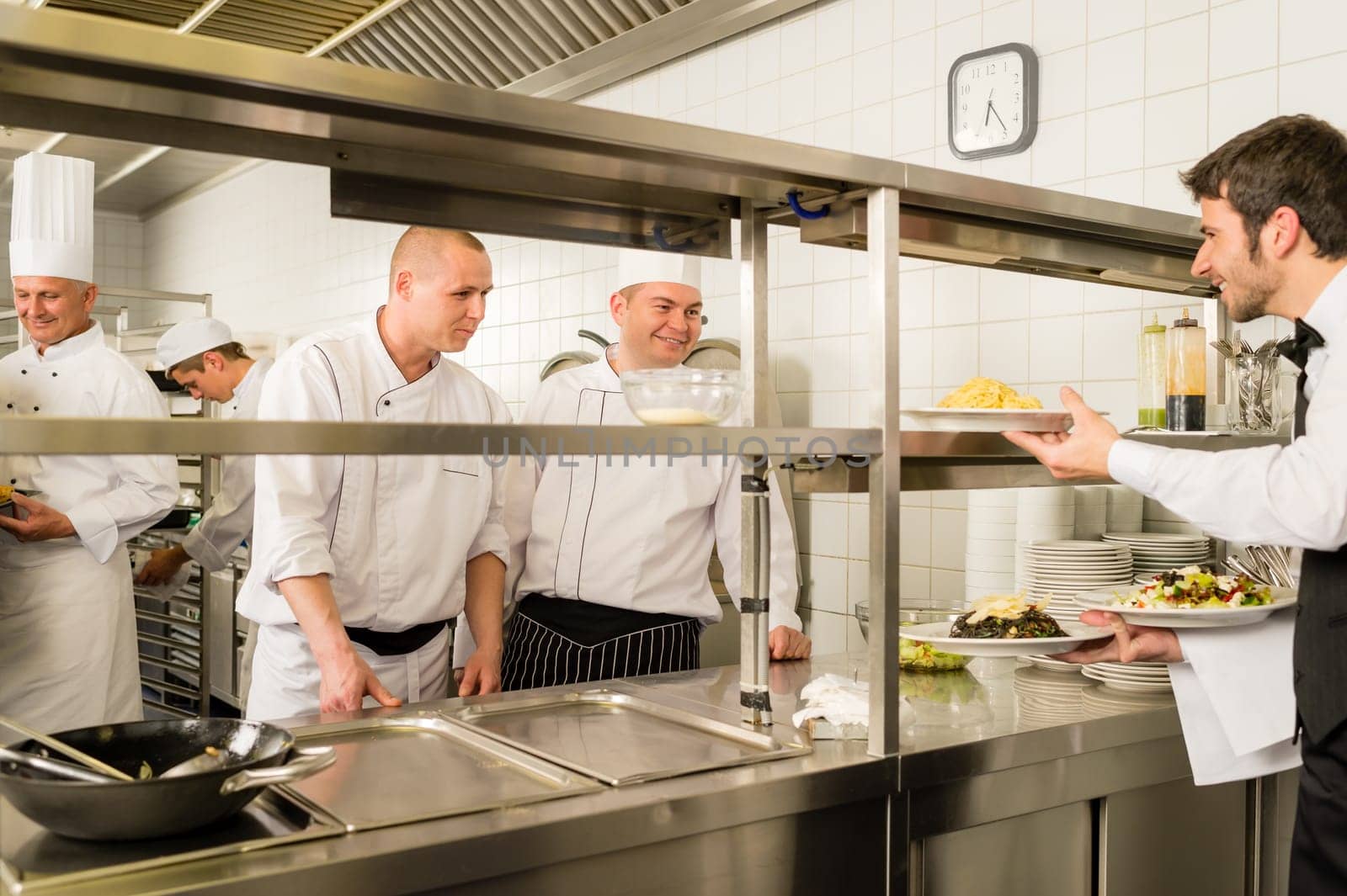 Restaurant waiter take meals from professional cook stainless kitchen