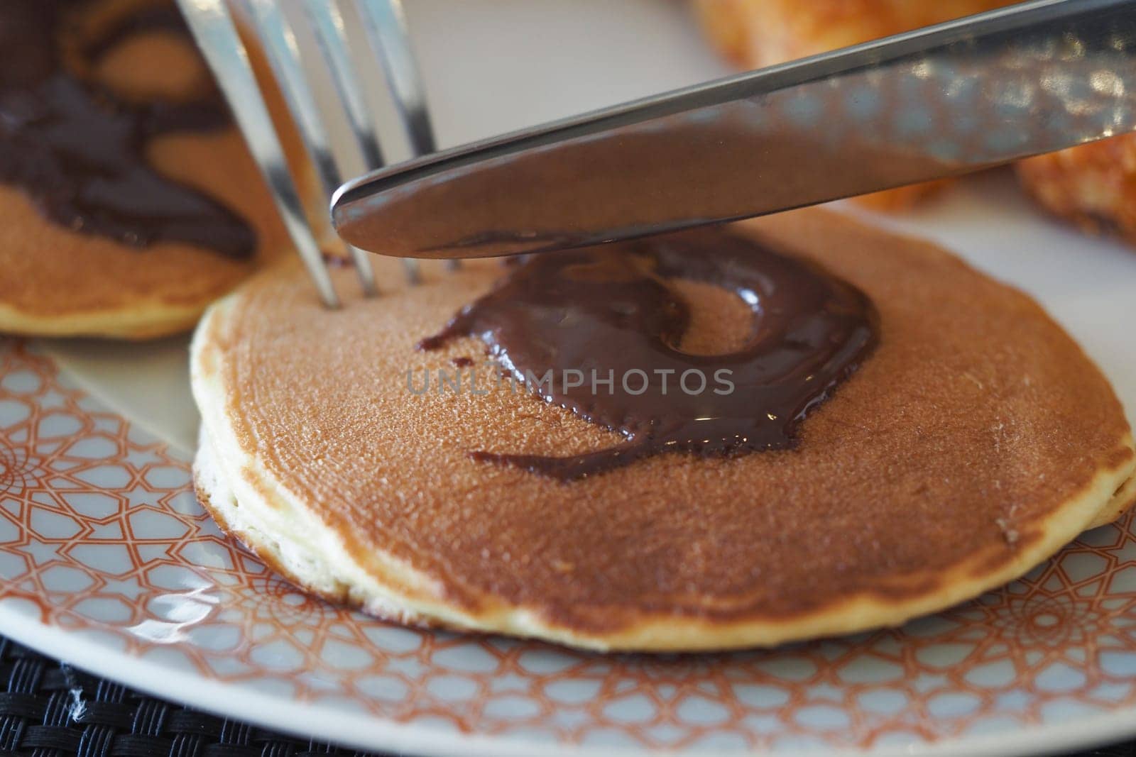 Fluffy pancakes topped with rich chocolate spread during breakfast time.