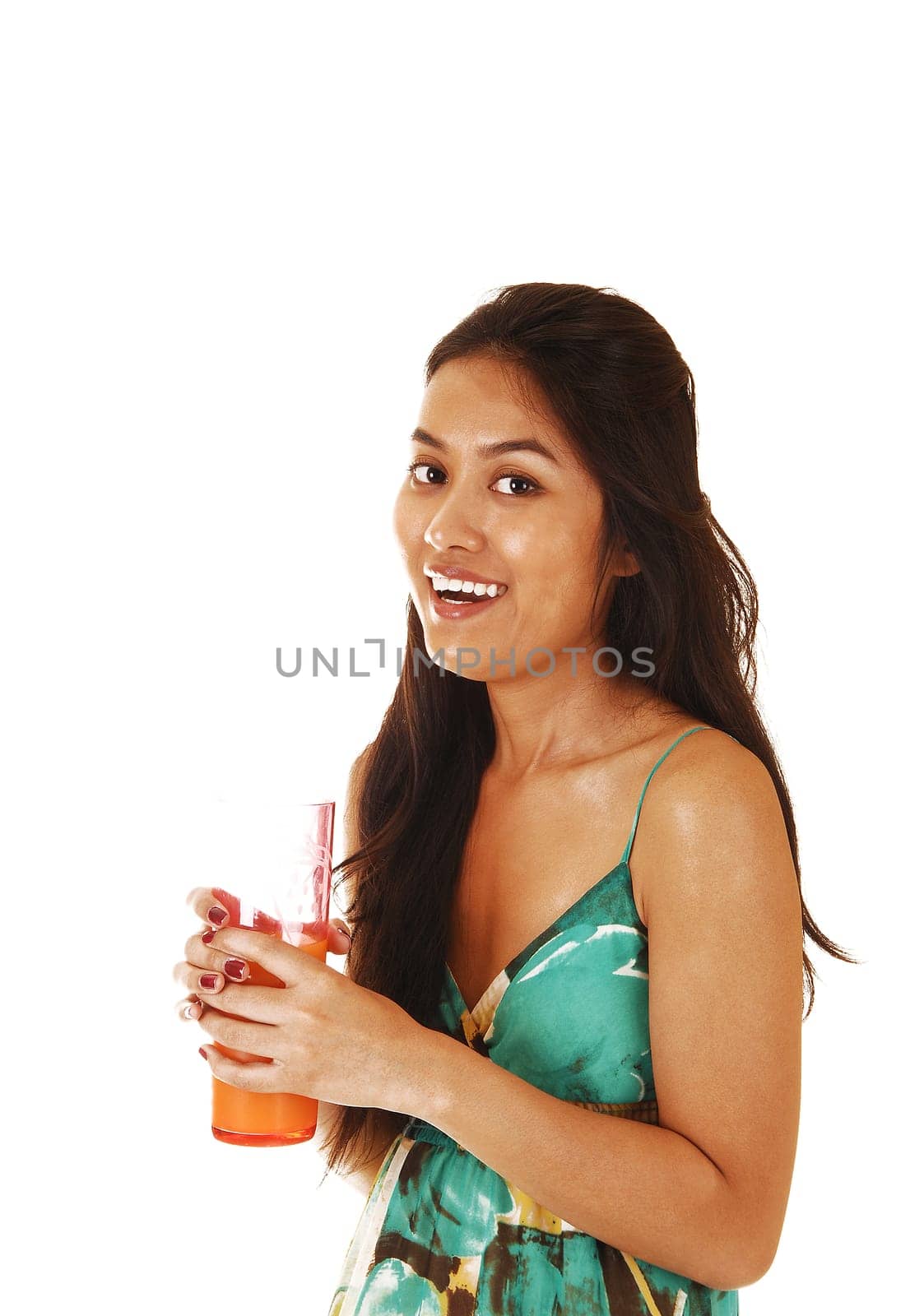 A young pretty Asian woman with a glass of juice in her hand laughing into the camera for white background.