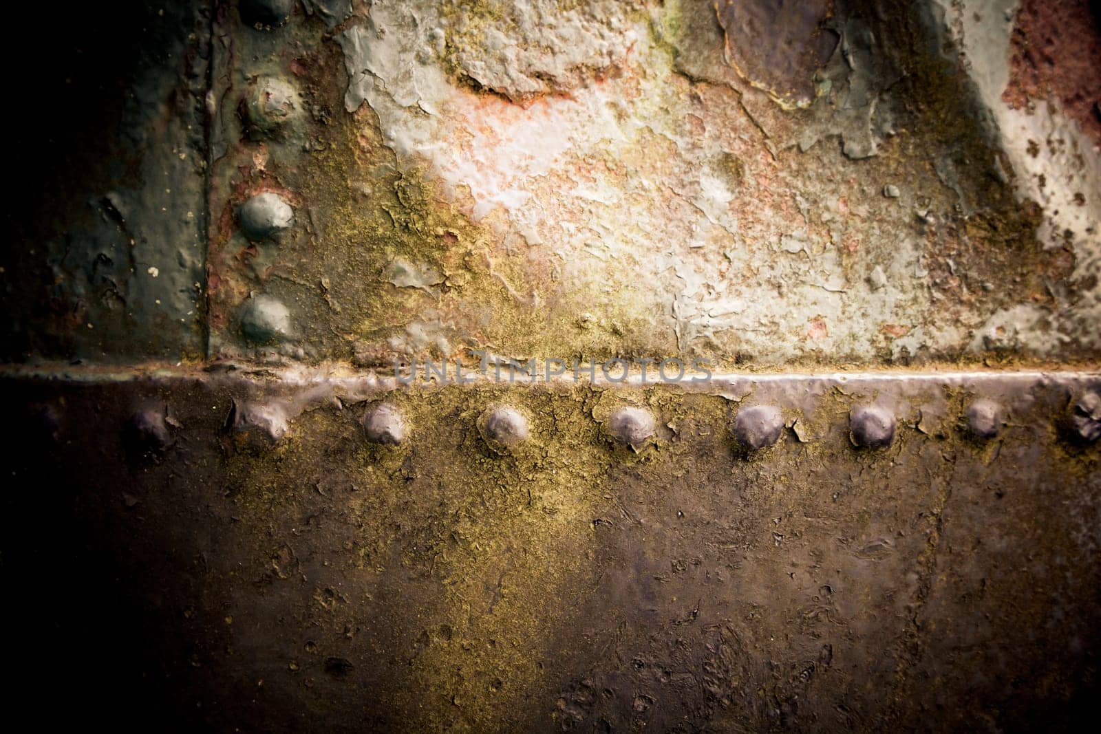 Grungy surface texture of rusted weathered old iron with rivets joining the plates of metal