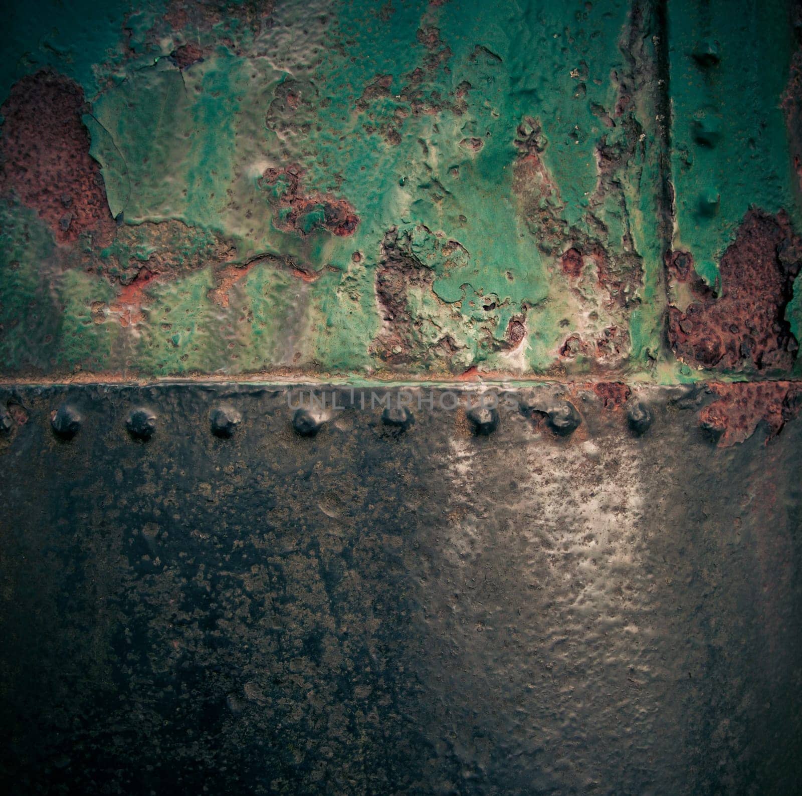 Grungy rusty old iron texture with weathered green paint and a riveted join with vignetting