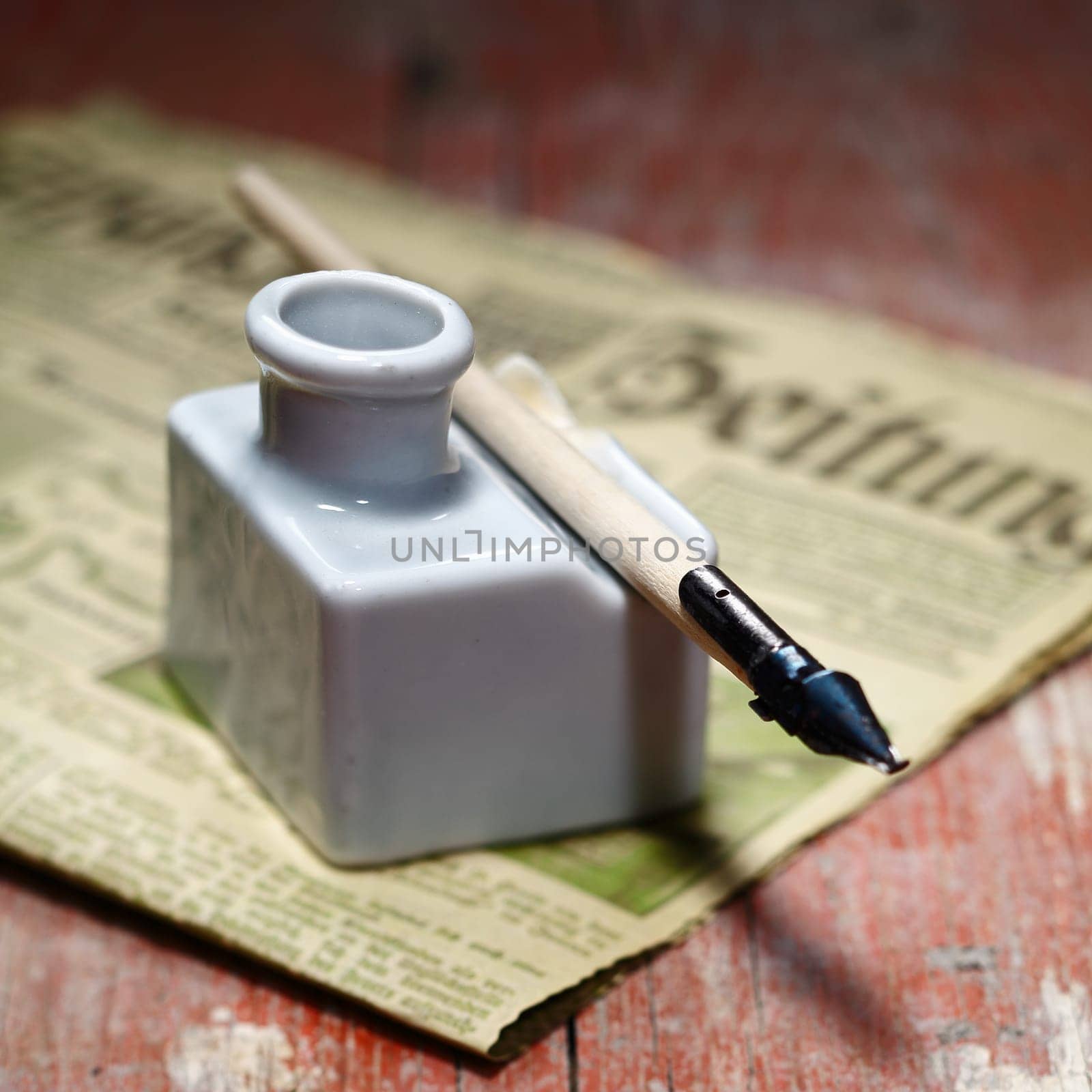 Old Ink Quill and an antique newspaper on an ancient wooden background