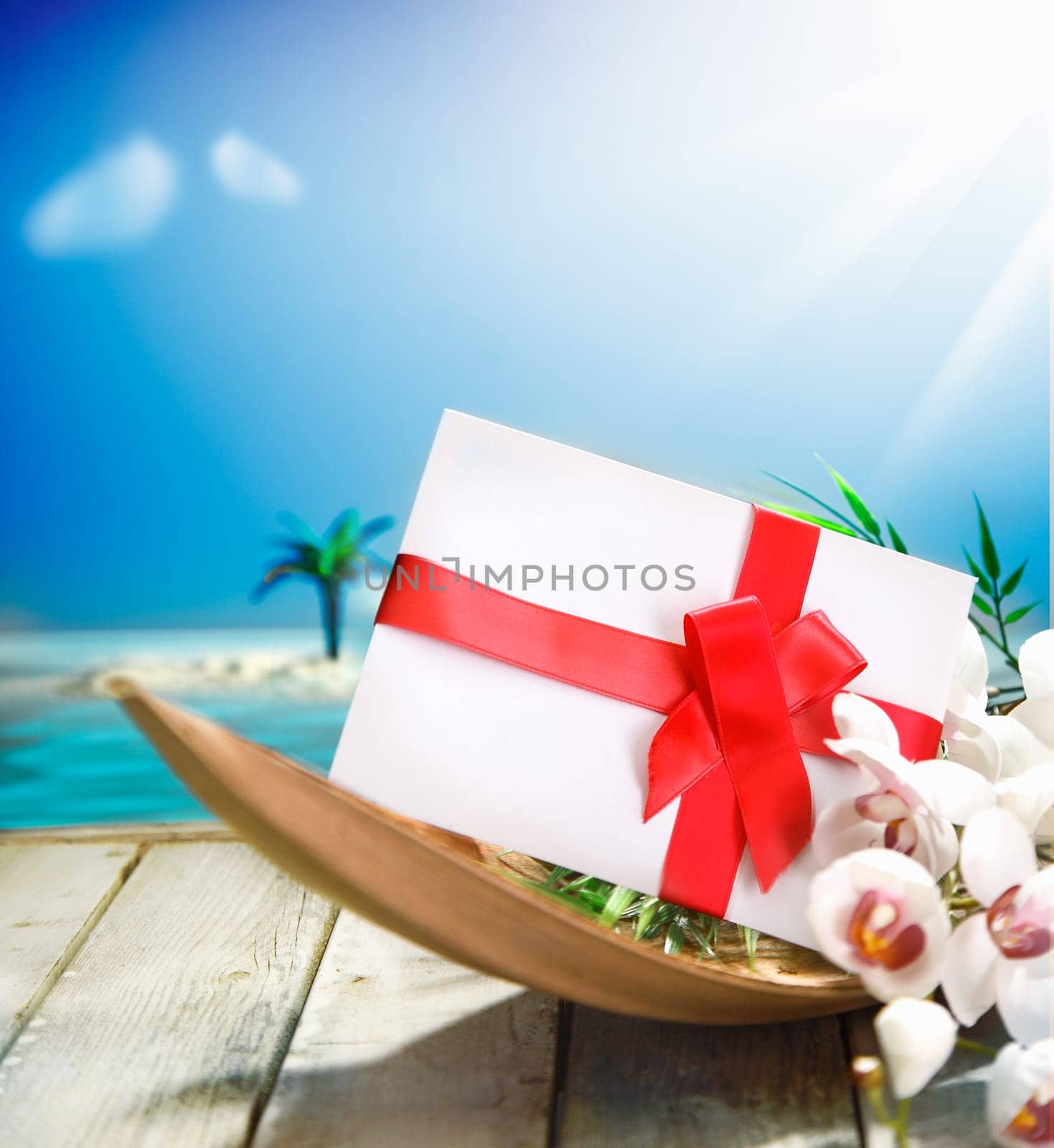 Romantic gift or envelope decorated with red ribbon and a bow on a wooden deck overlooking the ocean in a in tropical paradise