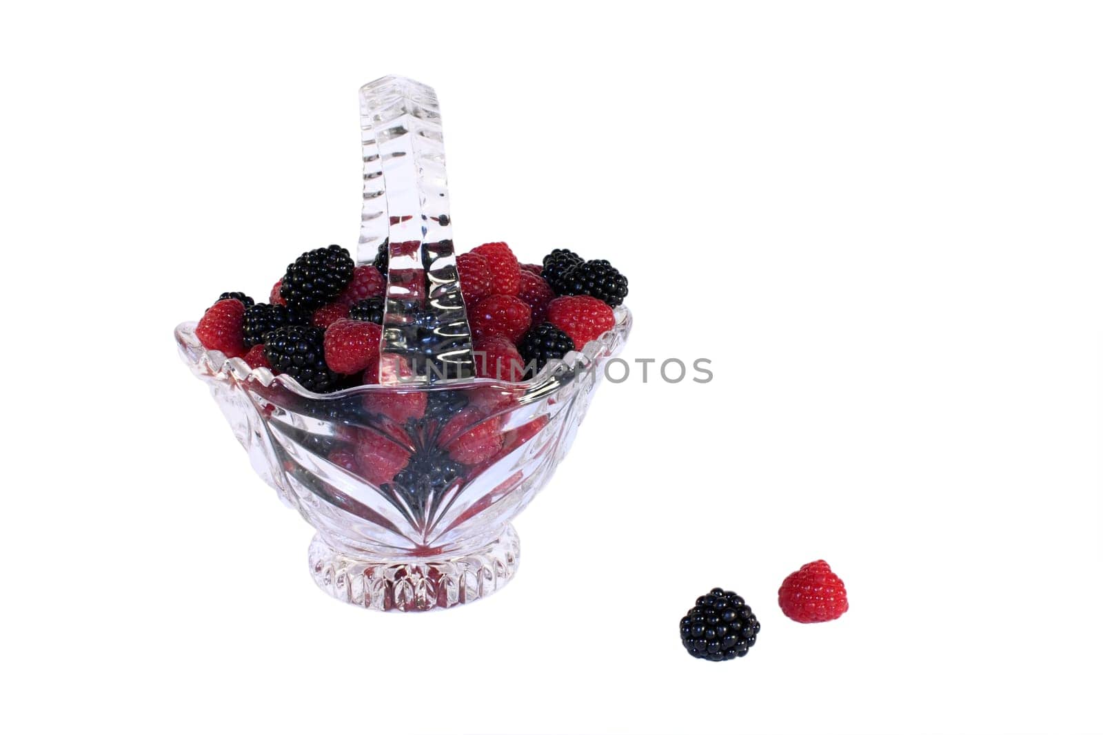 Glass basket full of fresh raspberries and blackberries