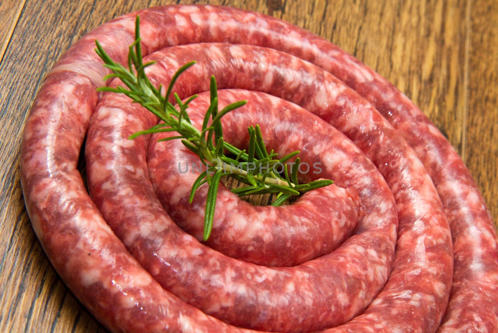 fresh raw sausage with rosemary on wooden table