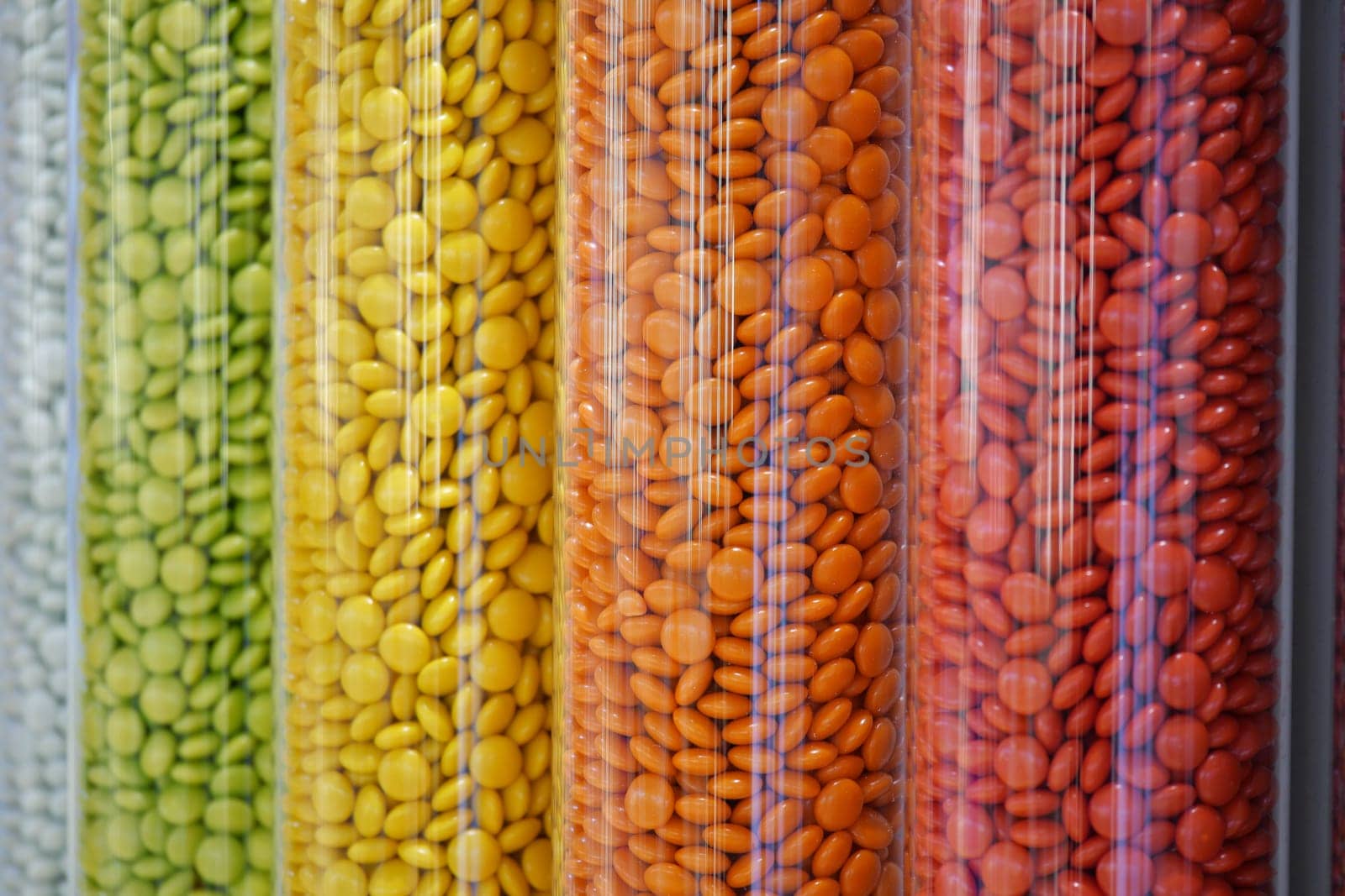 Brightly colored candies arranged in tall transparent containers at a market.