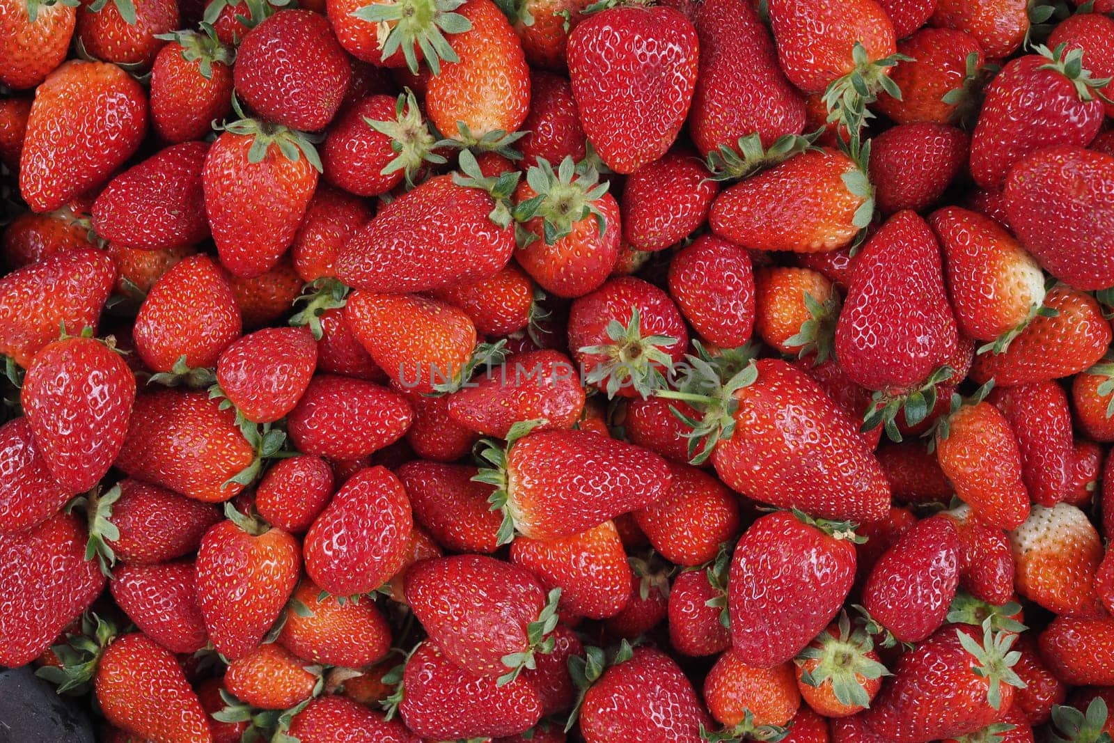Baskets of ripe strawberries are displayed at a vibrant summer market.