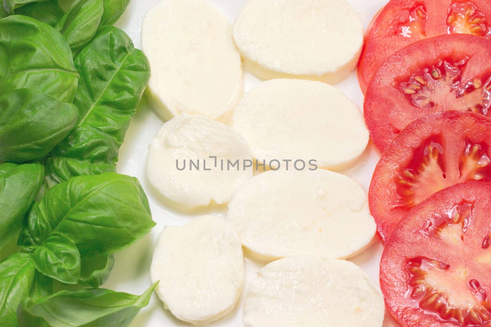 Mozzarella, tomatoes and basil leaves that make up the Italian flag.