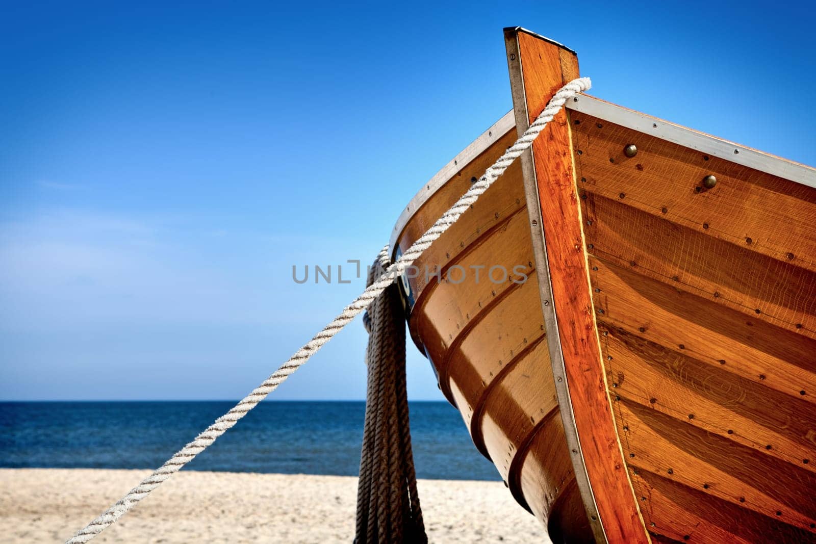 Front view of a wooden fishing boat, sea in background and blue sky with copyspace