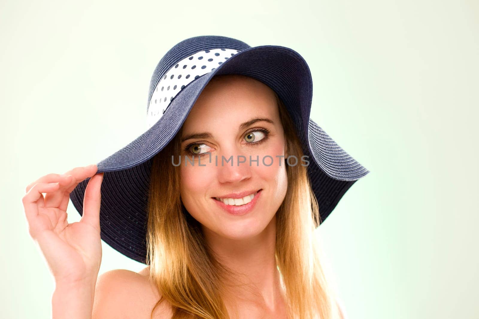 Portrait of a woman with a summer hat against a light green background
