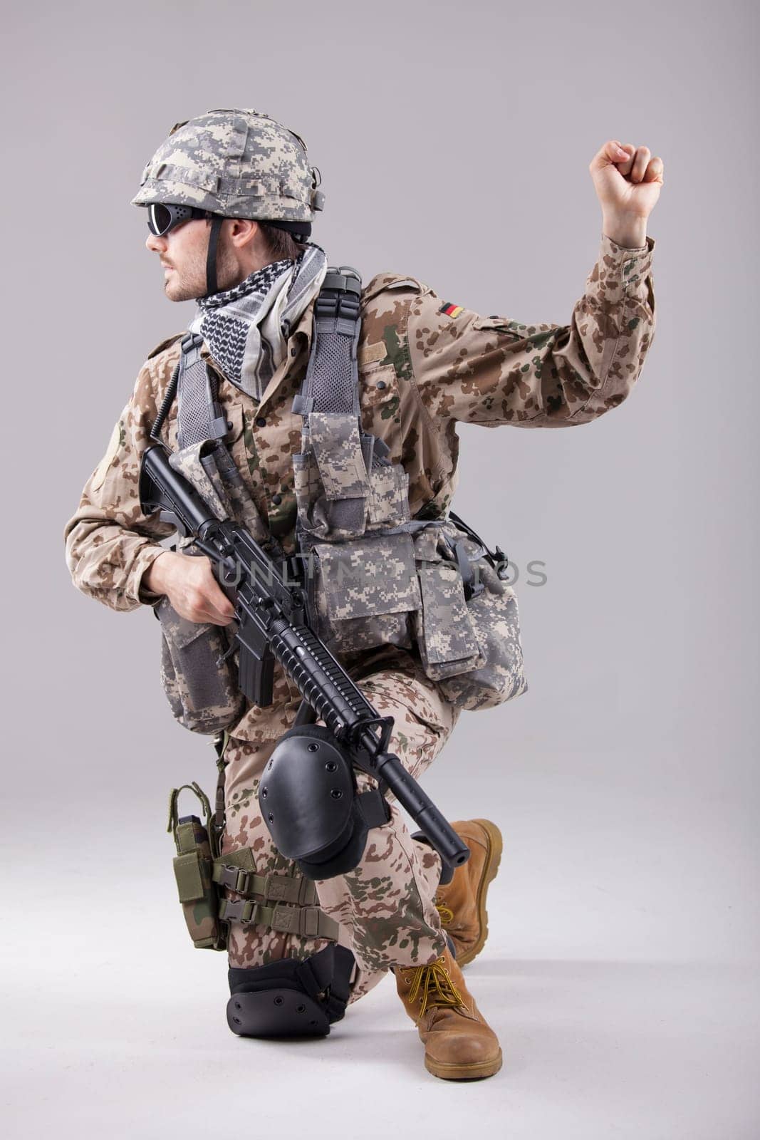 armed soldier kneeling with hand warning or stop gesture