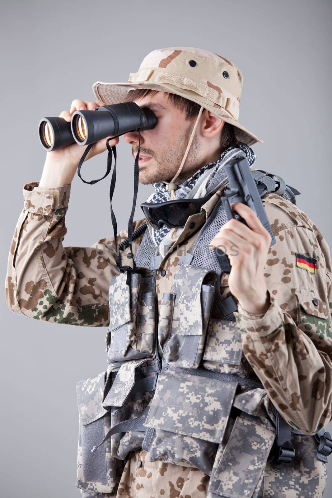 Soldier with handgun looking through binoculars