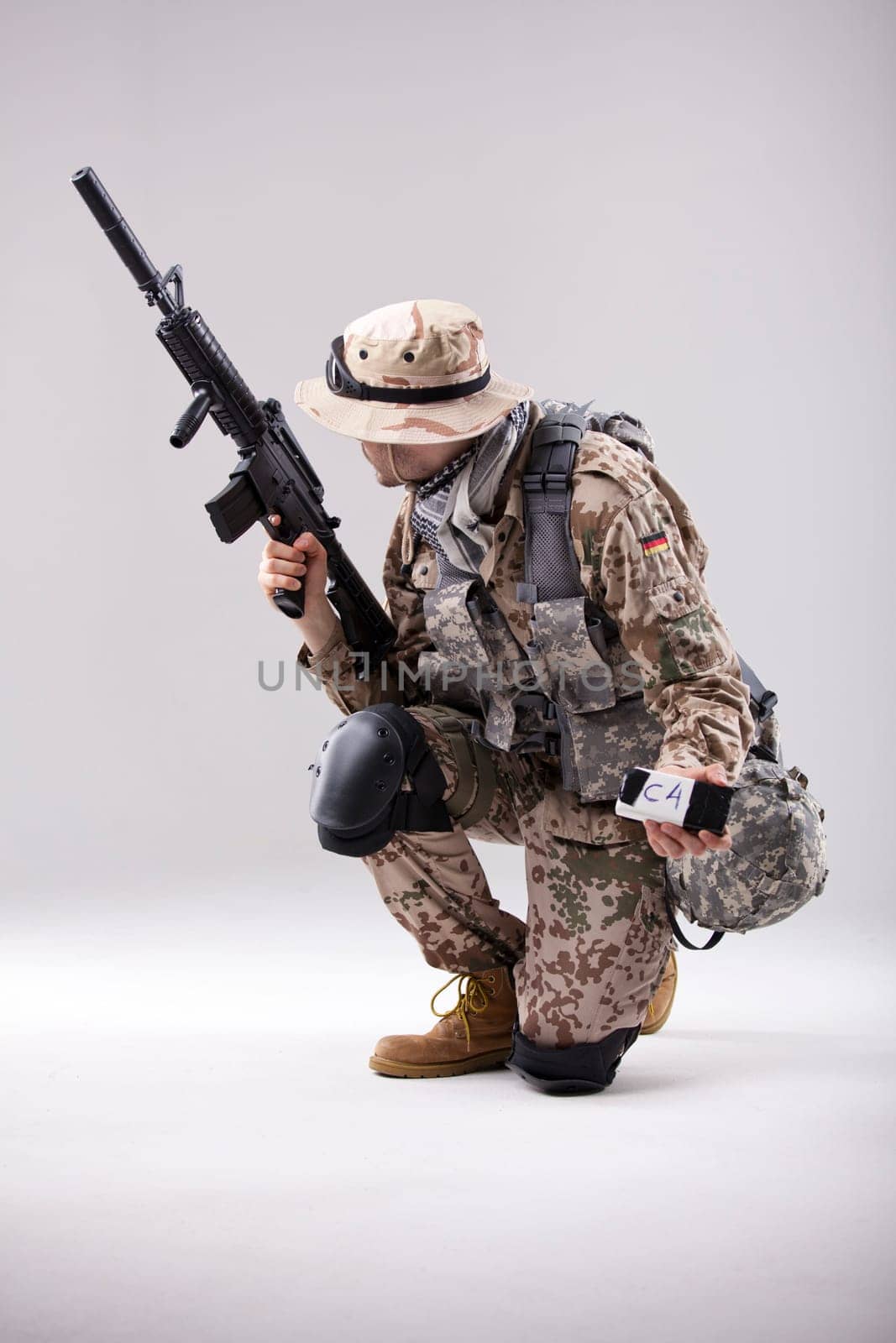 Armed Soldier in camouflage with explosive in his hand - shot in white studio