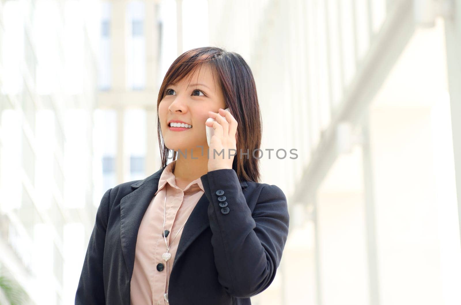 Asian Businesswoman walking on street passing by an office building.