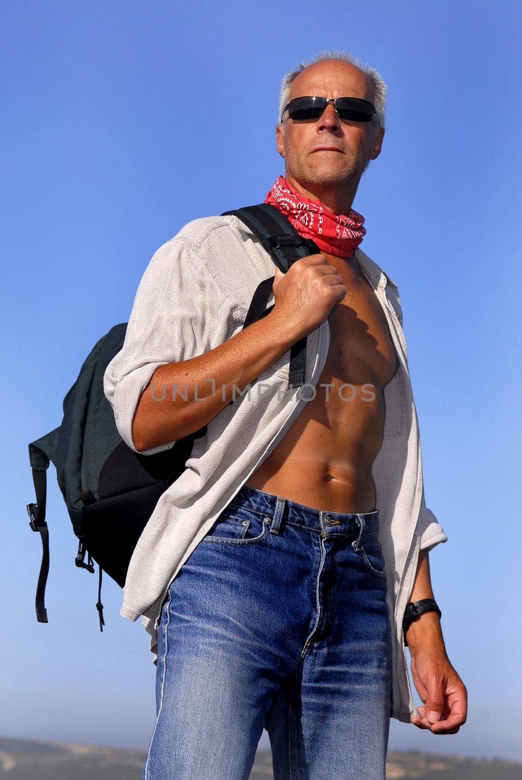 Handsome mature model posing with a backpack outdoors